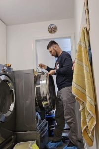 technician taking out dryer drum during repairs