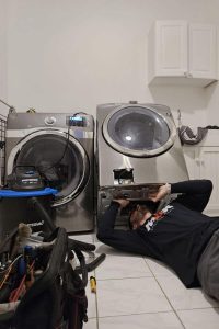dryer repair technicians underneath the dryer checking the electrical components
