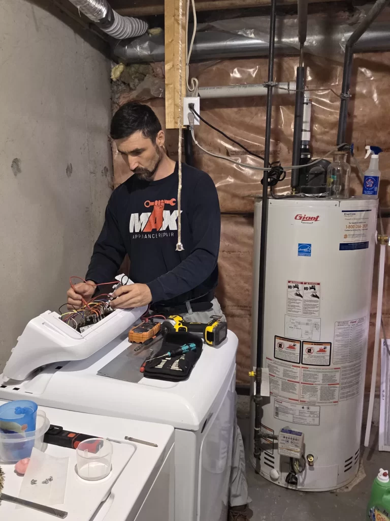 Technician working with the GE dryer control console open and wiring visible