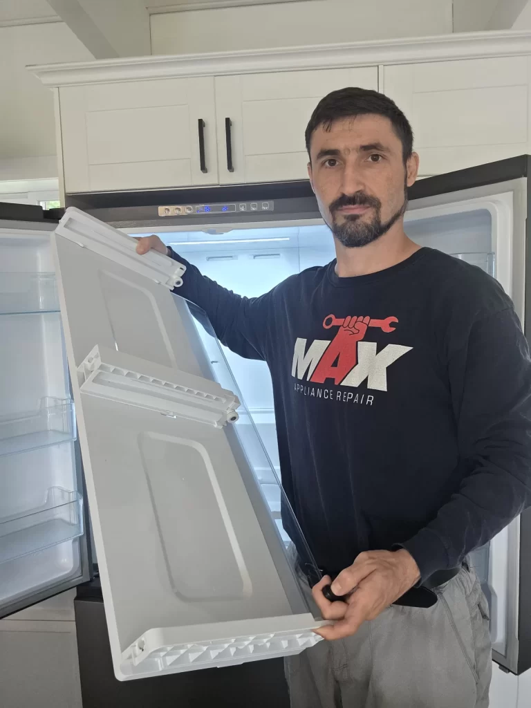 Technician holding the removed water tank inside a Hisense refrigerator