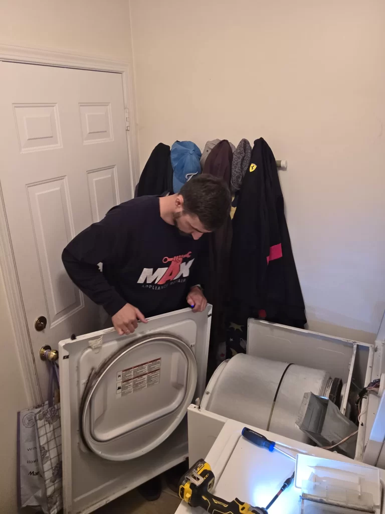 Technician holding the removed front panel beside the Whirlpool dryer drum