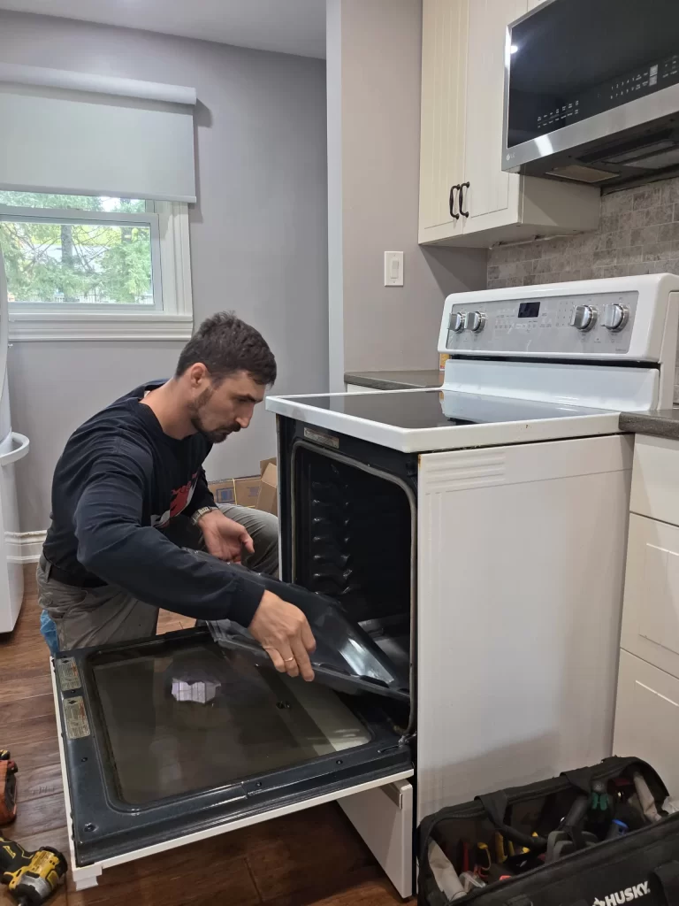 Technician lifting the bottom panel from the Whirlpool oven cavity