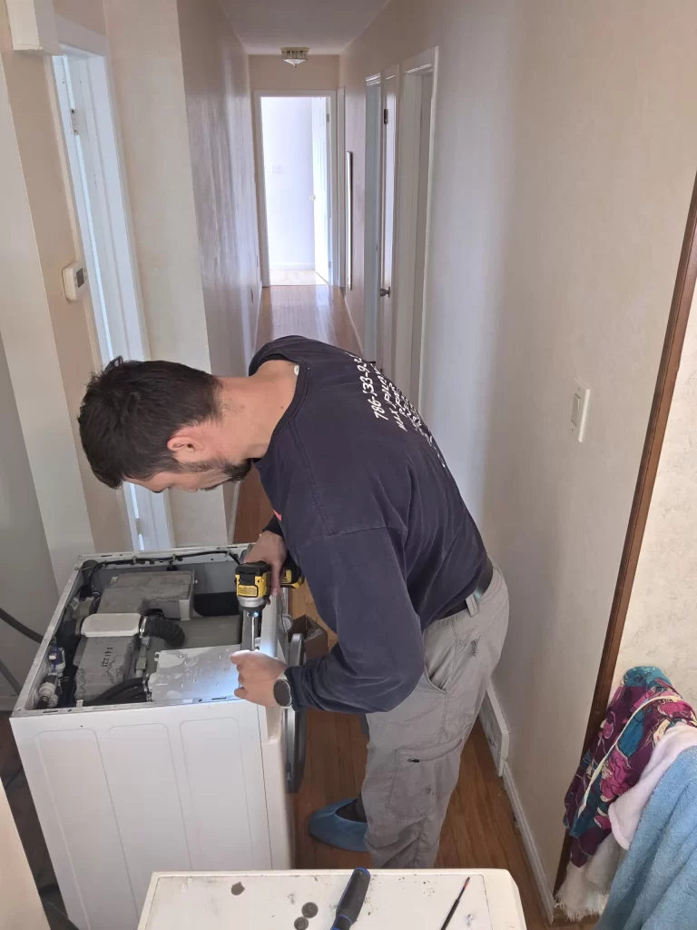 Technician using a driver with the top panel removed from a Whirlpool washer