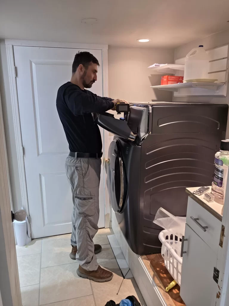 Technician removing the upper console from a GE washer dryer combo