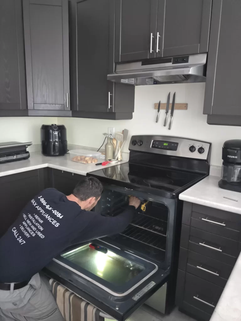 Technician working at the rear of the open GE electric oven cavity